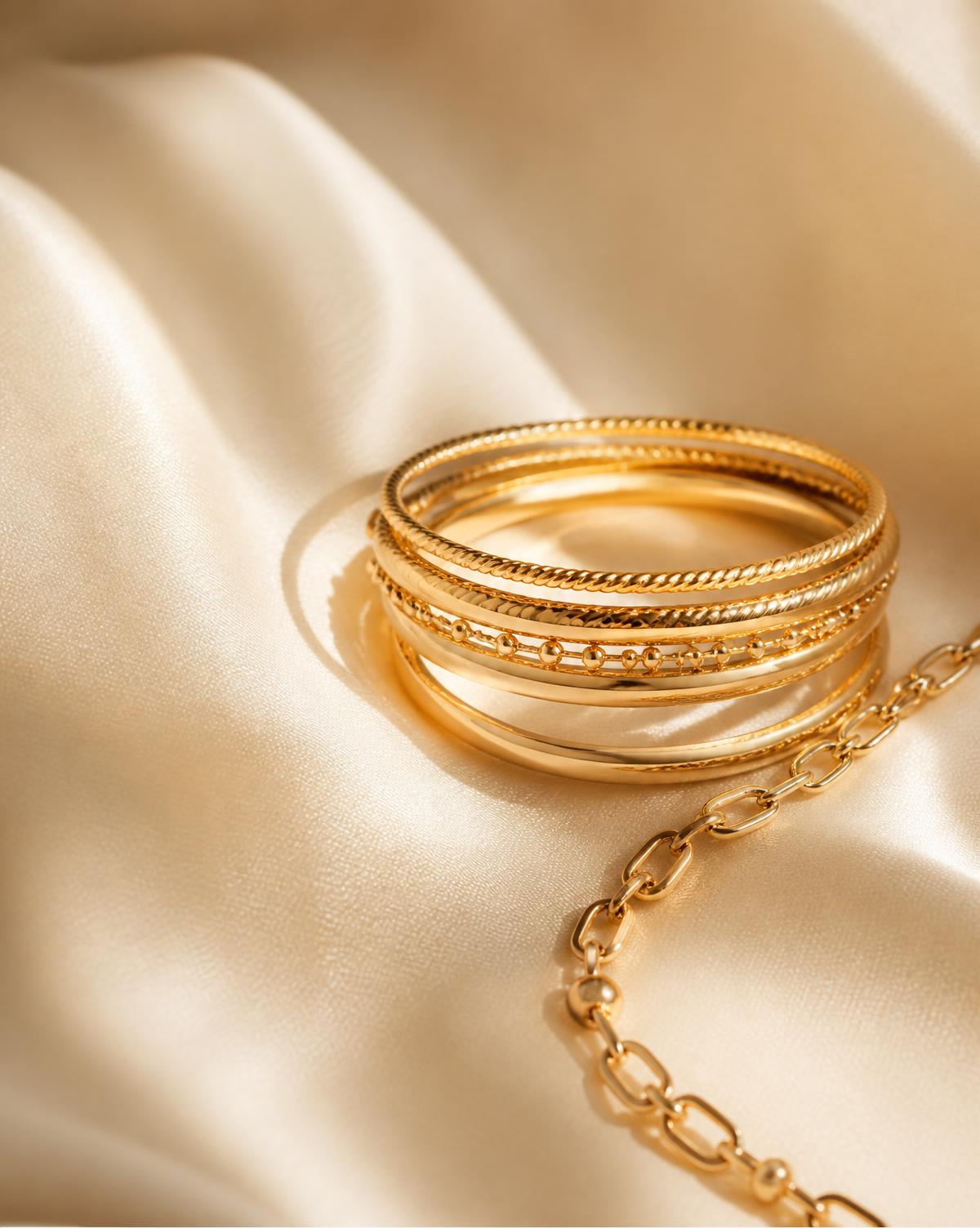 Set of slim polished gold bangles on ivory silk
